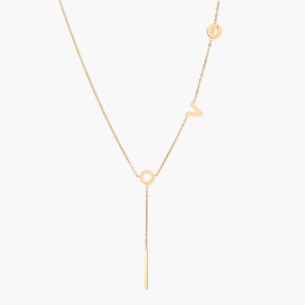 Gold Y-shaped necklace with L-O-V-E letter charms and vertical bar pendant on delicate chain against cream background